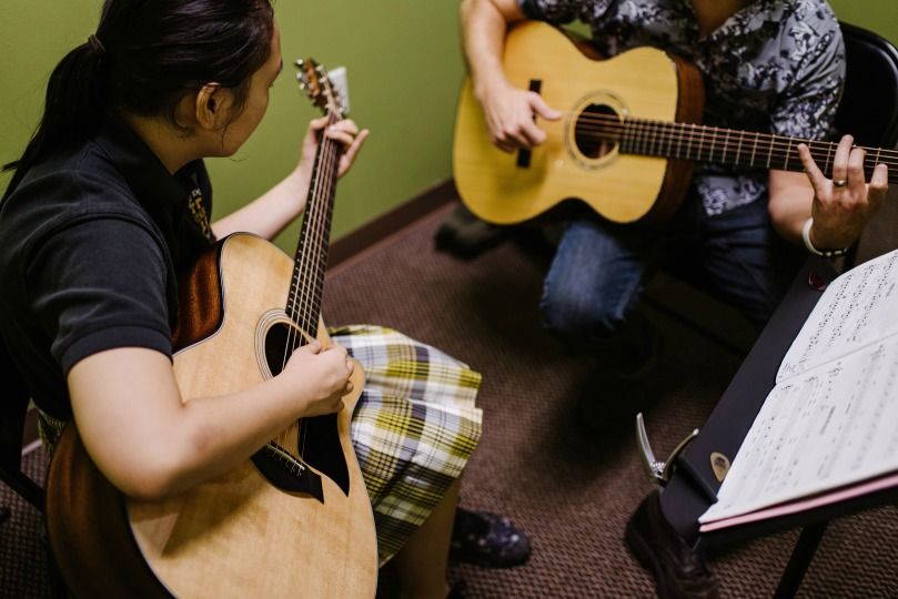 guitar teacher playing duet with student